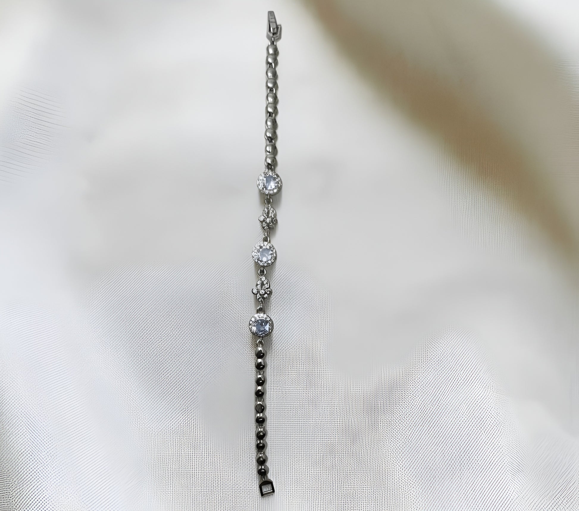 Silver bracelet with diamond-like beads on a white fabric background