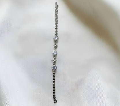 Silver bracelet with diamond-like beads on a white fabric background