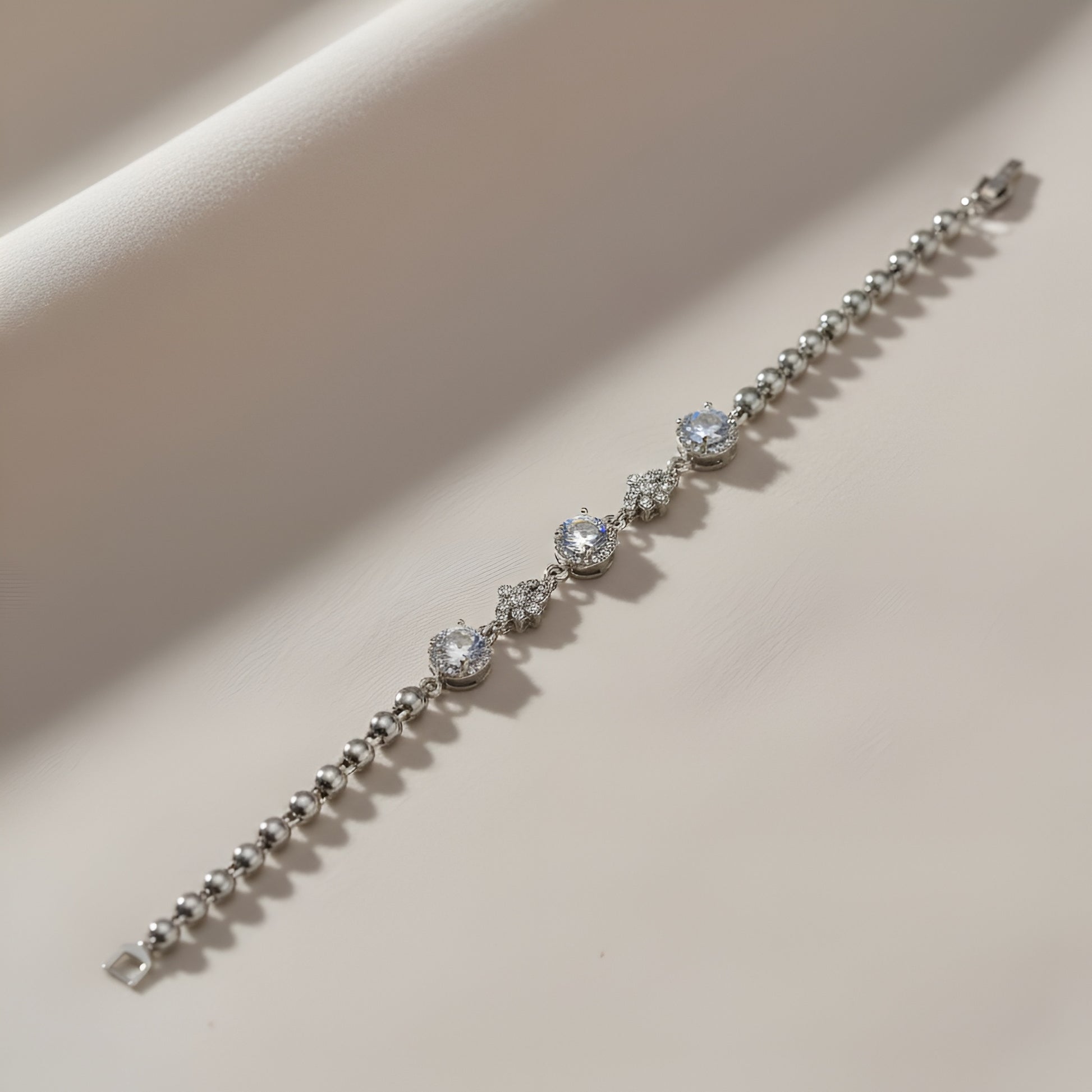 Silver bracelet with diamond-like stones on a beige background